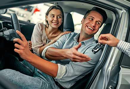 Young couple receiving the keys to their new car.