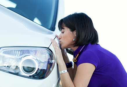 Young woman kissing her new vehicle.